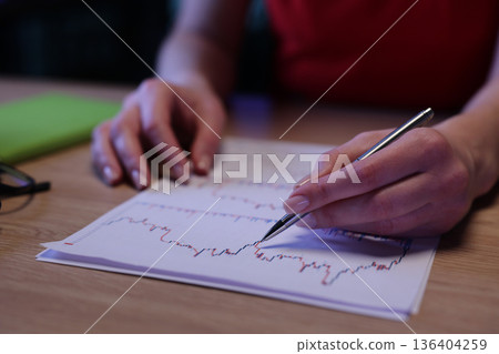 Analyzing data trends with focused attention in a cozy workspace during the evening 136404259