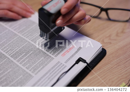 Creative hand stamping leaves an impression on important documents during an office filing session Creative hand stamping leaves an impression on important documents during an office filing session 136404272