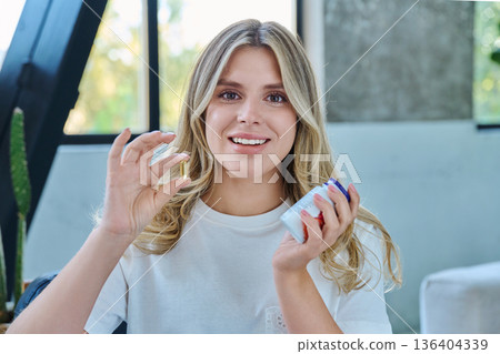 Close up of yellow Omega 3, fish oil capsule and bottle in hands of young woman Close up of yellow Omega 3, fish oil capsule and bottle in hands of young woman 136404339