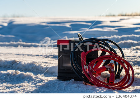 Car battery against the background of a car in winter. Winter battery discharge concept, copy space Car battery against the background of a car in winter. Winter battery discharge concept, copy space 136404374