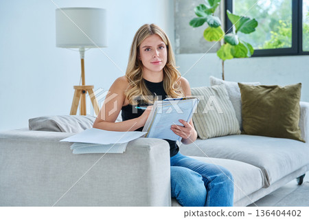 Young smiling student female study at home on couch with books, textbooks 136404402