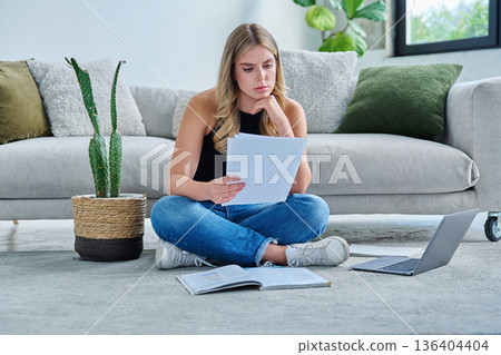 Serious sad young woman with business important papers in home interior Serious sad young woman with business important papers in home interior 136404404