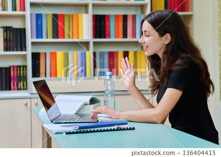 Teenage girl high school student having video lesson, at library 136404415