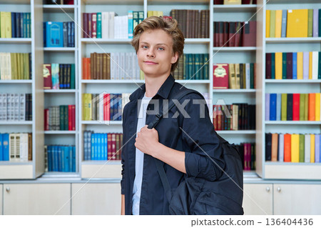 Portrait of serious teenage student with backpack in classroom library Portrait of serious teenage student with backpack in classroom library 136404436