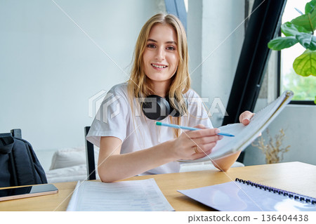 Webcam portrait female college student, sitting at home at the table with textbooks 136404438