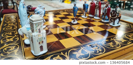 A close-up of a decorative chessboard with detailed medieval-style pieces. Conceptual representation of leadership, competition, decision-making, business strategy, and critical thinking. 136405684