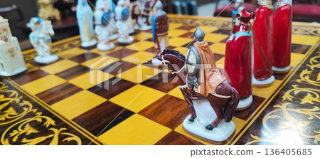 A close-up of a decorative chessboard with detailed medieval-style pieces. Conceptual representation of leadership, competition, decision-making, business strategy, and critical thinking. 136405685