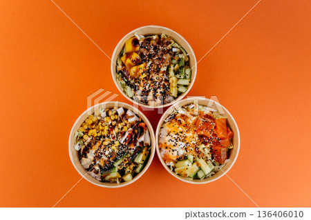Three poke bowls with rice, salmon, tofu and veggies on orange background Three poke bowls with rice, salmon, tofu and veggies on orange background 136406010