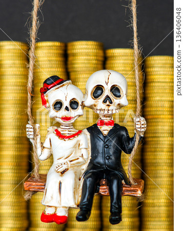 Skeleton bride and groom on swing in front of gold coin stacks symbolizing love, wealth, inheritance Skeleton bride and groom on swing in front of gold coin stacks symbolizing love, wealth, inheritance 136406048