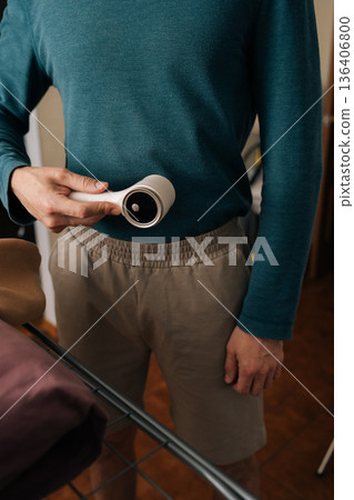 Person holding fabric shaver, cleaning lint from various garments, enhancing textile longevity, and performing essential laundry and clothing maintenance tasks. Person holding fabric shaver, cleaning lint from various garments, enhancing textile longevity, and performing essential laundry and clothing maintenance tasks. 136406800
