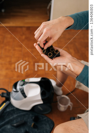 Closeup vertical cropped shot of man holding handful of metal brushes with brass bristles for steam cleaner, selecting and preparing accessories for various cleaning tasks, efficient deep scrubbing. Closeup vertical cropped shot of man holding handful of metal brushes with brass bristles for steam cleaner, selecting and preparing accessories for various cleaning tasks, efficient deep scrubbing. 136406803
