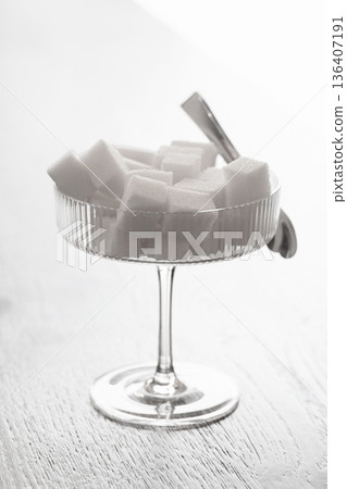 A stylish still life featuring white sugar cubes piled in a crystal coupe glass 136407191