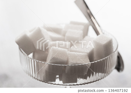 A still life photography featuring white sugar cubes piled in a crystal coupe glass 136407192