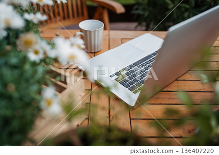 Laptop on wooden garden table in spring Laptop on wooden garden table in spring 136407220