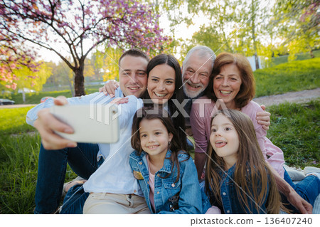 Three generation family sitting outside in spring nature, taking selfie. 136407240