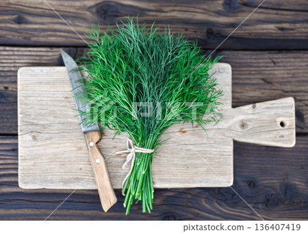 Fresh dill bunch tied with string on wooden cutting board 136407419