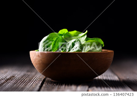 Fresh green spinach foliage in wooden bowl on rustic surface Fresh green spinach foliage in wooden bowl on rustic surface 136407423
