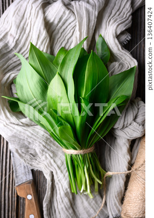 Fresh wild garlic leaves placed on textured kitchen cloth 136407424