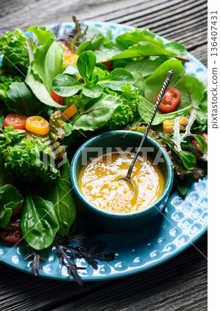 Mixed salad greens with cherry tomatoes and yellow dressing 136407431