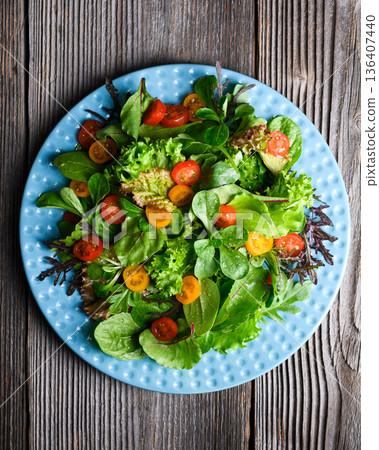 Salad mix with lettuce leaves and cherry tomatoes on a blue plate 136407440