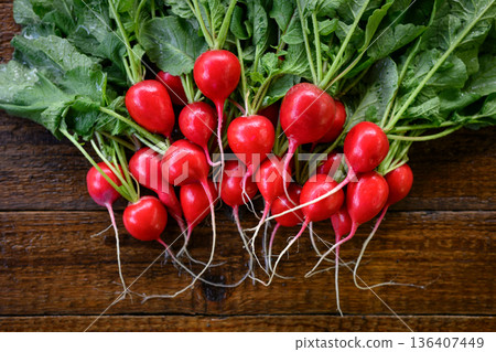 Whole red radishes with stems and roots on wooden surface 136407449