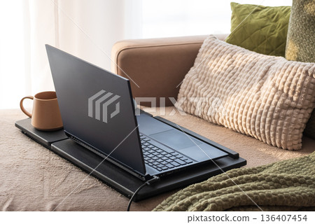 Laptop and Coffee Mug on Lap Desk. Cozy Morning Home Workspace with Green Accents Laptop and Coffee Mug on Lap Desk. Cozy Morning Home Workspace with Green Accents 136407454