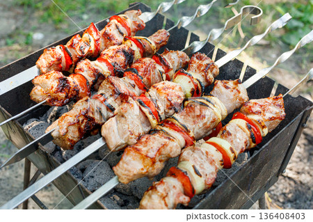 Cooking barbecue with vegetables on skewers. Roasted meat on the grill Cooking barbecue with vegetables on skewers. Roasted meat on the grill 136408403