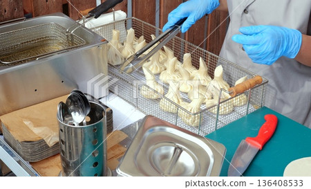 Vendor crafting freshly prepared dumplings, Street food vendor assembling hot handmade dumplings, Fastpaced market setting with vendors meticulously preparing fragrant handmade dumplings for cooking Vendor crafting freshly prepared dumplings, Street food vendor assembling hot handmade dumplings, Fastpaced market setting with vendors meticulously preparing fragrant handmade dumplings for cooking 136408533
