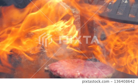 Flame engulfing burger patty over grill, grill master taming intense blaze, sparks and smoke swirling, dramatic orange flames licking meat, fastpaced street food action, bold charred flavors Flame engulfing burger patty over grill, grill master taming intense blaze, sparks and smoke swirling, dramatic orange flames licking meat, fastpaced street food action, bold charred flavors 136408642