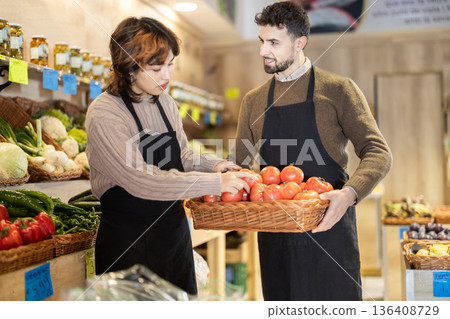 Man and woman seller putting tomatoes 136408729
