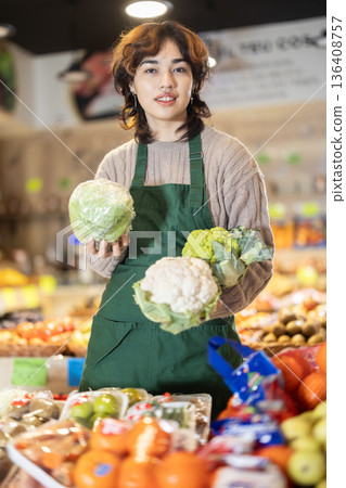 Young female seller offering cauliflower in grocery market 136408757