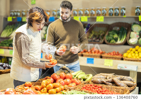 Young couple choose tomatoes in store in store Young couple choose tomatoes in store in store 136408760
