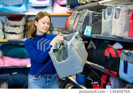 Woman choosing fabric pet carrier bag for cats in pet shop 136408768