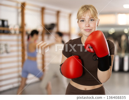 Girl coach in boxing gloves is standing in gym 136408835