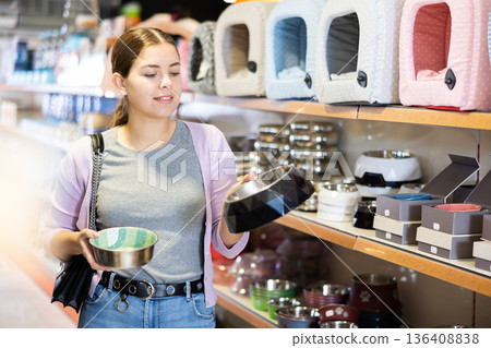 Young happy woman choosing bowl for pets in pet shop 136408838