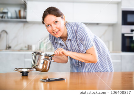 Portrait of a housewife preparing soup in a pot in kitchen 136408857
