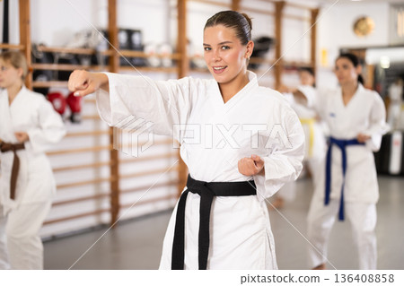 Women students repeat position and perform sequence of punches and painful techniques kata 136408858