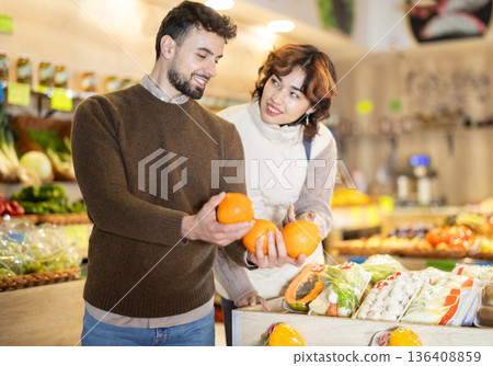 Married couple choose oranges together at grocery supermarket 136408859