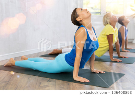 Mother, grandmother and teen son do exercise upward facing dog pose, Urdhva Mukha Svanasana pose Mother, grandmother and teen son do exercise upward facing dog pose, Urdhva Mukha Svanasana pose 136408898