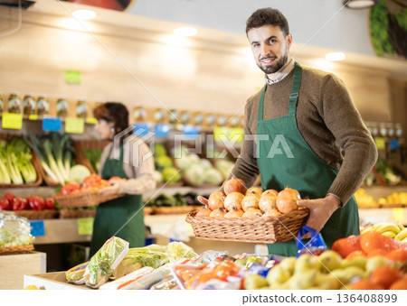 Young man seller puts pomegranates in store Young man seller puts pomegranates in store 136408899