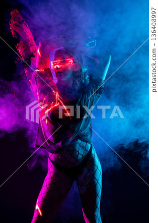 Cyberpunk woman wearing glowing visor and fishnets posing in vibrant neon pink and blue light. Cyberpunk woman wearing glowing visor and fishnets posing in vibrant neon pink and blue light. 136408997