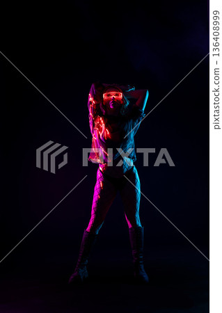 Futuristic woman in LED glasses dancing in neon lights with laser beams and smoke Futuristic woman in LED glasses dancing in neon lights with laser beams and smoke 136408999