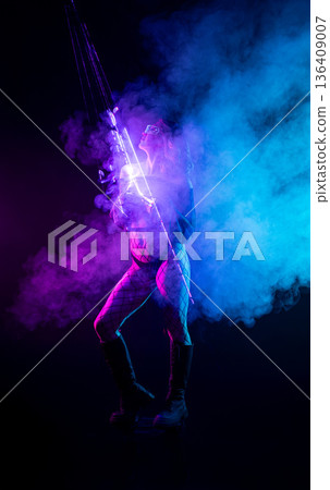 Cyberpunk woman with neon light staff posing in pink and blue smoke on a black background 136409007