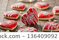 Heart shaped cookies with red icing and white sprinkles on a rustic wooden table. Homemade Valentine's Day sweet treats. Romantic dessert concept 136409092