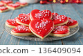 Red heart shaped cookies with sprinkles on a glass plate. Valentine's Day sweet treat on blue wooden background 136409094