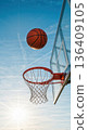 A successful basketball shot about to go through the hoop. Vertical action photo of scoring a goal outdoors against a sunny blue sky 136409105