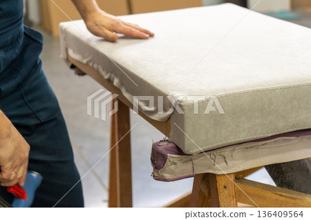 Worker's hand operates a blue pneumatic stapler. Worker's hand operates a blue pneumatic stapler. 136409564