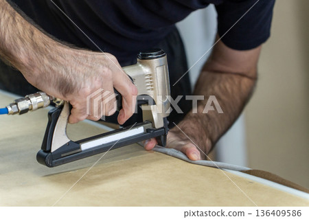 A person uses a pneumatic stapler A person uses a pneumatic stapler 136409586