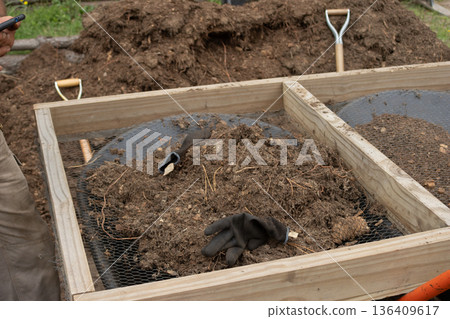 Sifting organic soil and compost for sustainable reforesting and garden preparation, using hand tools outdoors 136409617