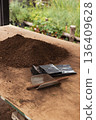Vertical real picture of rich soil and organic compost mix on a wooden surface with a small shovel for planting trees 136409628